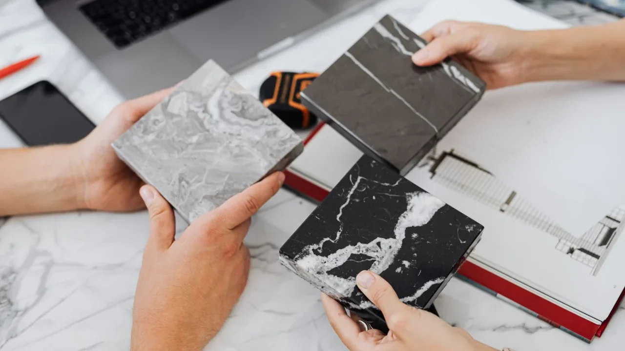 Maini care compara trei mostre de placi ceramice, in nuante diferite