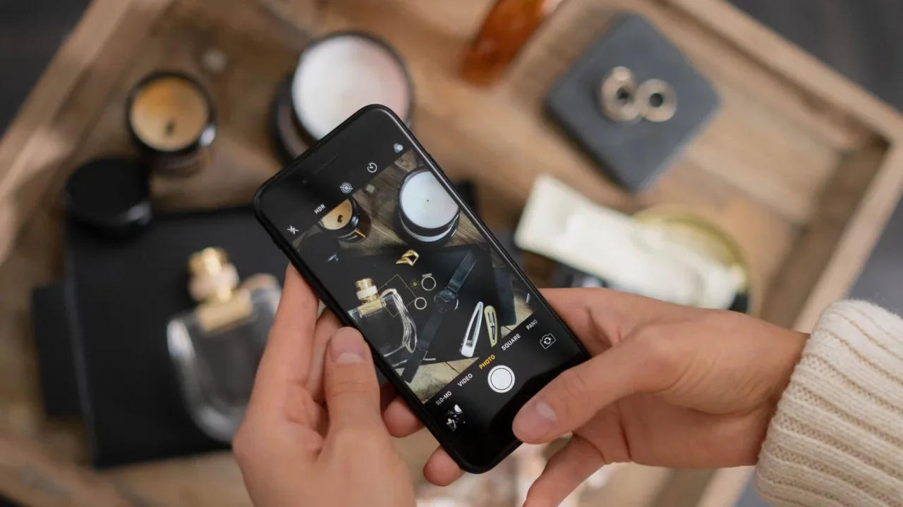 Maini care fotografiaza cu telefonul obiecte asezate pe o tava de lemn